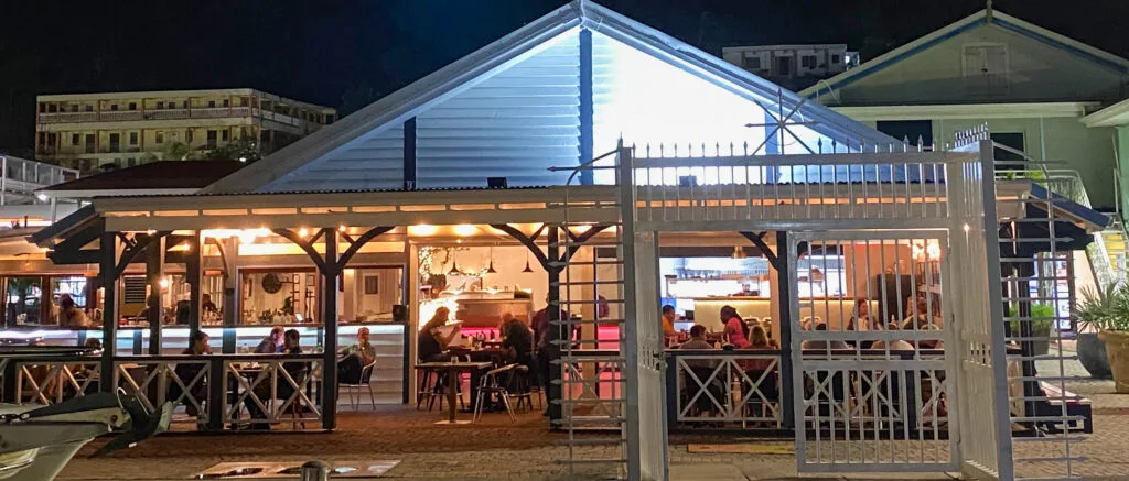 Aziana waterfront dining room glowing at night beside Bobby's Marina